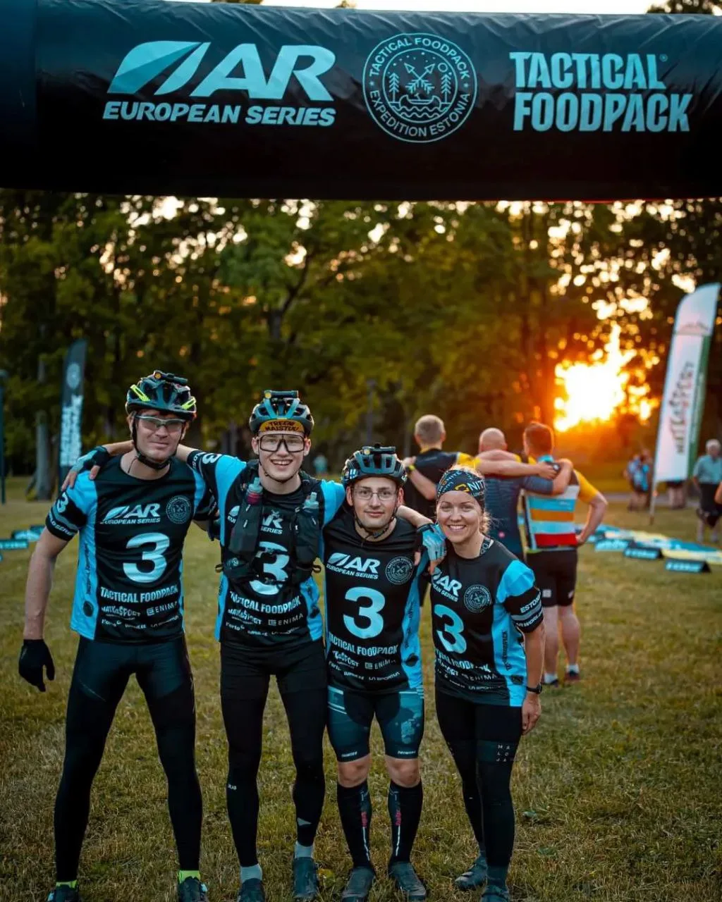 Neljä tiimin jäsentä maalikaaren alla Tactical Foodpack Expedition Estonia -kisassa auringonlaskussa